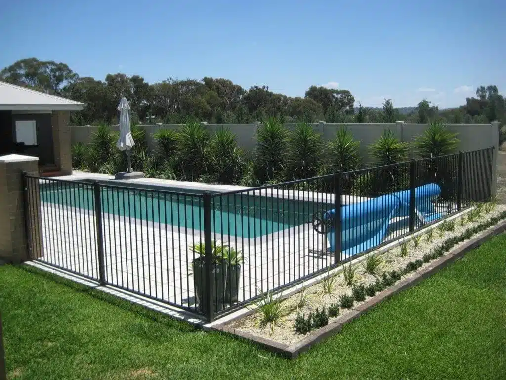Black aluminium pool fencing around a backyard pool