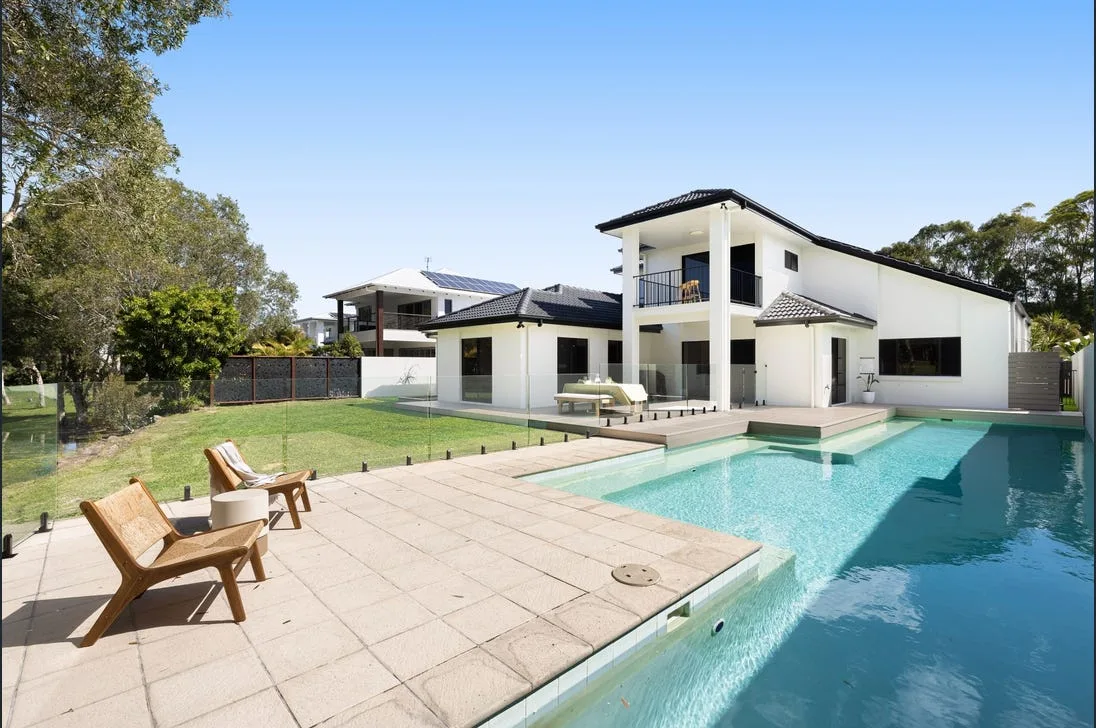 Frameless glass pool fencing beside a large modern home