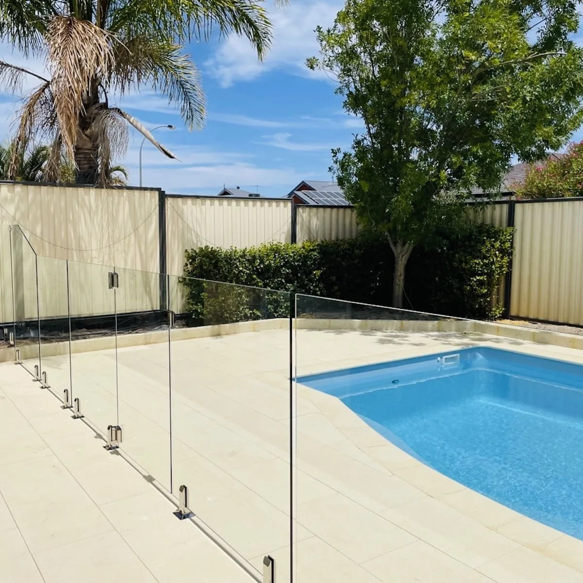 Glass pool fencing around a landscaped backyard pool